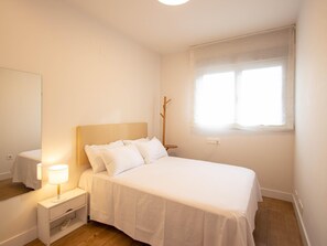Un dormitorio con cama, mesita de noche, lámpara y ventana con vistas.