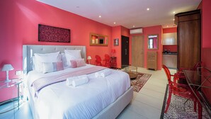 A hotel room with a large bed, a dining table with chairs, a kitchen area, and a bathroom. - Suite Rigaud Romantique (Perpignan)