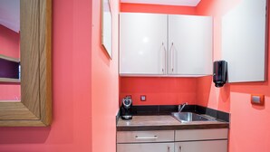 A compact kitchen with white cabinets, a stainless steel sink, and a coffee maker on the countertop. - Suite Rigaud Romantique (Perpignan)