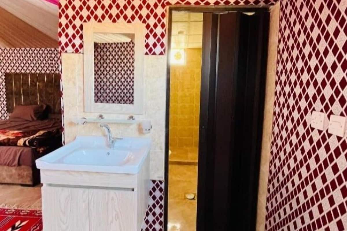Een badkamer met een wit wastafel, een spiegel en een behang met een patroon.