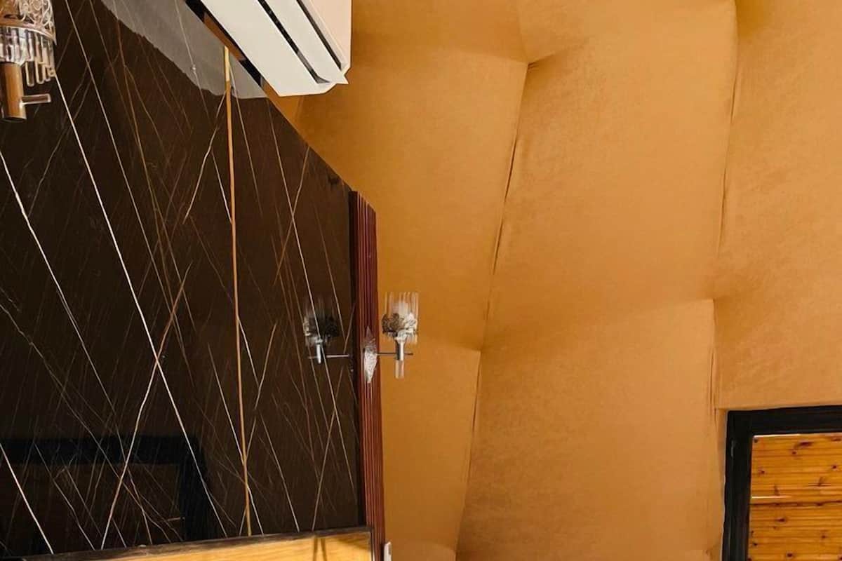 Een slaapkamer met een houten hoofdeinde, een bed met witte en blauwe kussens en een nachtkastje van hout.