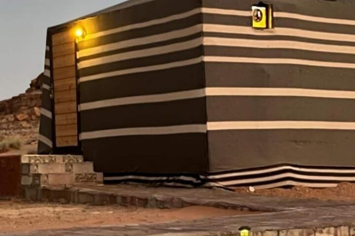 Een modern gebouw met horizontale strepen, een klein bordje aan de zijkant en een lantaarn in de buurt.
