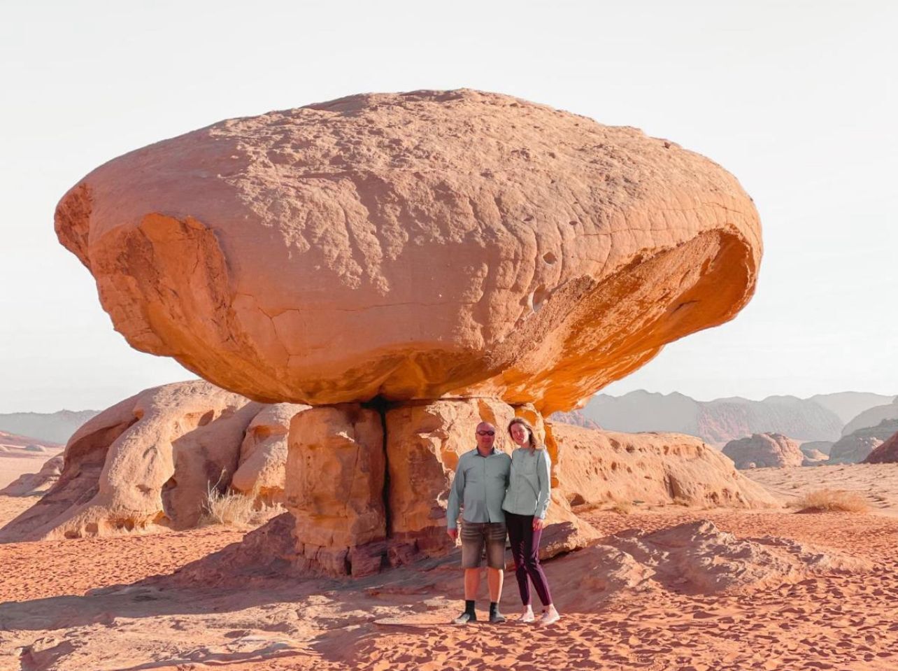 A large rock formation with two people standing underneath it.