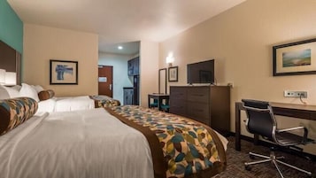 A hotel room with two beds, a desk with a chair, a television, and a dining area.