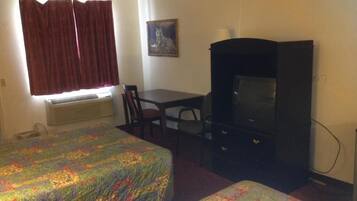 Een kamer met twee bedden, een bureau, een stoel, een televisie en een raam met gordijnen.