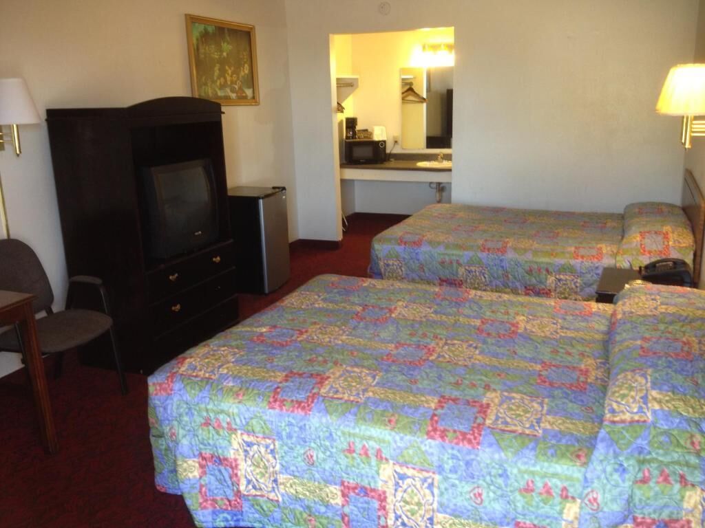 A hotel room with two beds, a television, a desk, and a mirror.