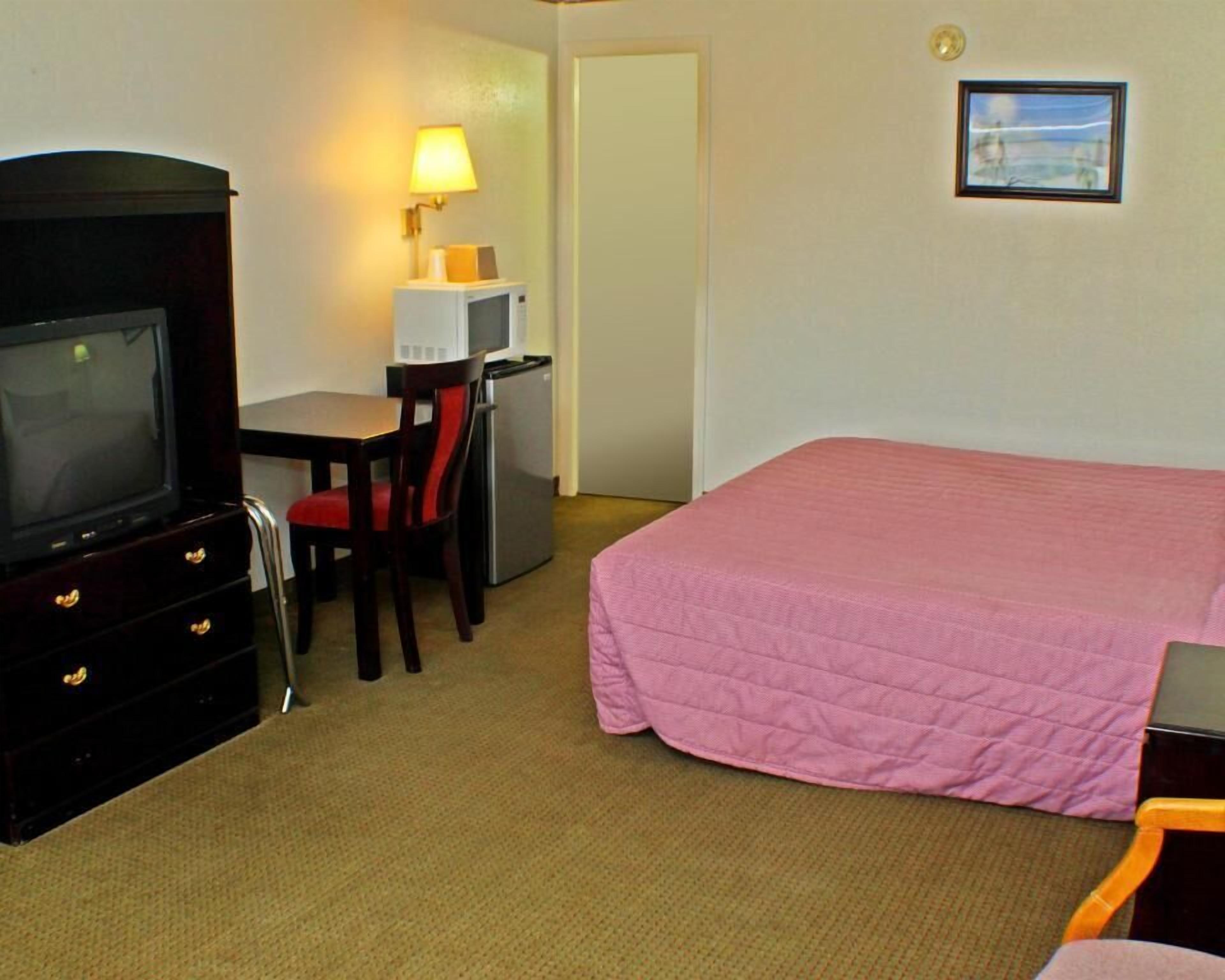 Une chambre d’hôtel équipée d’un lit, d’une télévision, d’un bureau avec une lampe et d’un réfrigérateur.