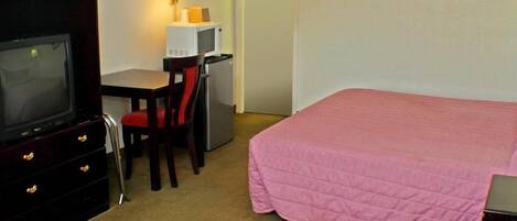 Une chambre d’hôtel équipée d’un lit, d’une télévision, d’un bureau avec une lampe et d’un réfrigérateur.