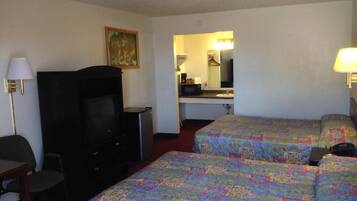 A hotel room with two beds, a TV, a desk, and a mirror.