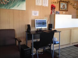 A reception desk with a computer monitor, a chair, and a small table.