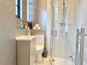 A modern bathroom with a glass shower enclosure, a toilet, and a sink with a mirror above it. - Sleek 1 Bedroom flat in Shoreditch, Old Street (London)