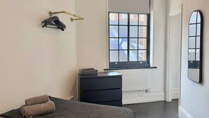 A bedroom with a bed, a dresser, a window, and a mirror. - Sleek 1 Bedroom flat in Shoreditch, Old Street (London)