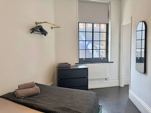 A bedroom with a bed, a dresser, a window, and a mirror. - Sleek 1 Bedroom flat in Shoreditch, Old Street (London)