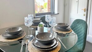 A dining table set with plates, bowls, and wine glasses, with a view of a building through a window. - Sleek 1 Bedroom flat in Shoreditch, Old Street (London)