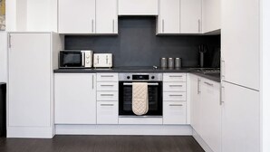 A modern kitchen with white cabinets, a microwave, a toaster, and an oven.