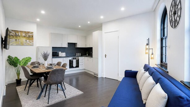 A modern living space with a dining area, kitchen, and seating area.