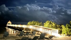 Un salon de plage doté de chaises longues et d’une terrasse en bois offrant une vue sur l’océan.