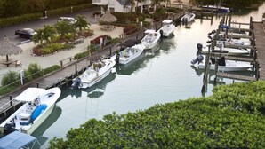 Un port de plaisance avec des bateaux amarrés, un bâtiment blanc avec un toit bleu et un coucher de soleil sur l’eau.