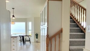 Um interior espaçoso com escadaria de madeira, área de cozinha e espaço de jantar.