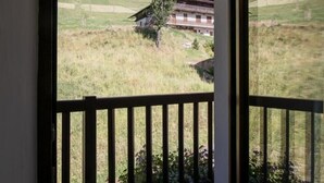 A view from a room with a balcony, overlooking a grassy field and a building with a balcony. - Residence Mont- Blanc Lodge - LA Fleche (HAUTELUCE)