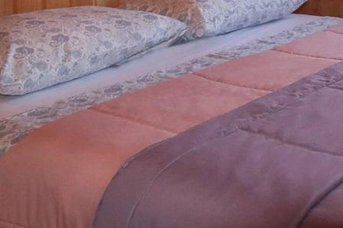 Een bed met een paars dekbed en een kussen met een patroon.