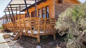 Une cabane en bois avec une véranda, un espace abrité et une petite fenêtre.