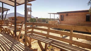 Une cabane en bois dotée d’un balcon, d’une terrasse en bois et offrant une vue dégagée sur le paysage environnant.