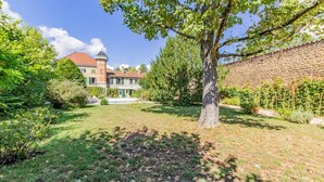 Ein großes Haus mit Garten, einer Steinmauer und einem Baum.