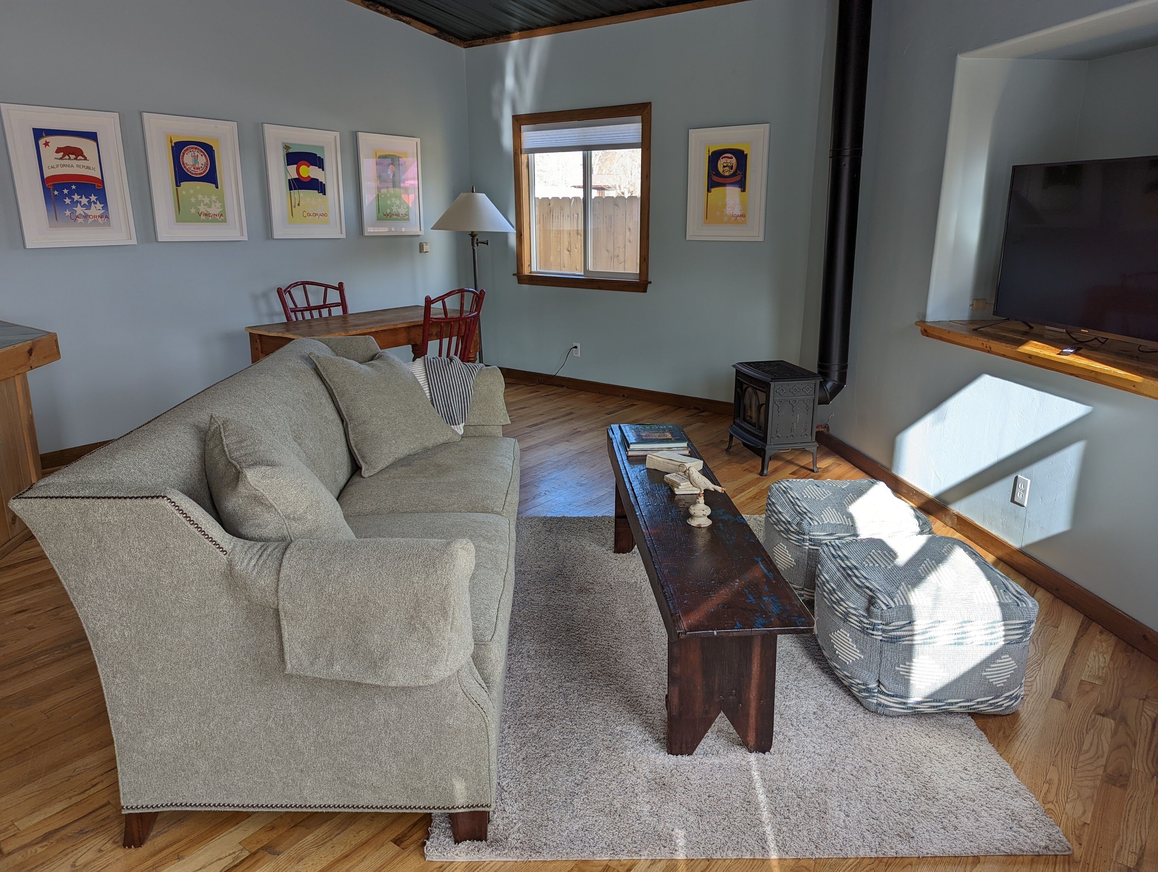 A living room with a sofa, a coffee table, a rug, and framed state flags on the wall.