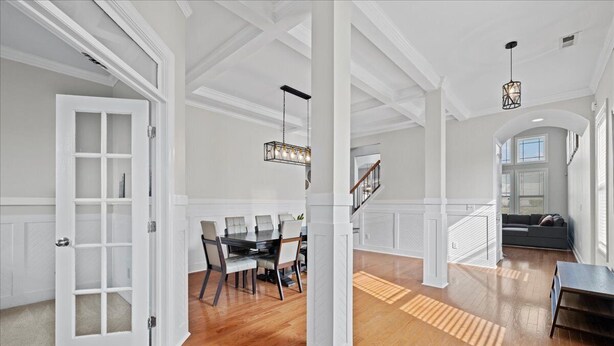 Un amplio salón con piso de madera, una mesa de comedor con sillas, una escalera y un sofá.