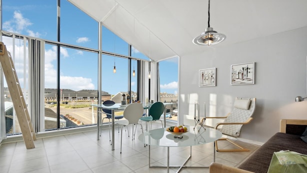 A spacious room with large windows, a round glass table, and modern furniture. - Awesome apartment in Fanø with WiFi (Fanø)