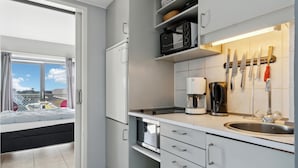 A modern kitchen with white cabinets, a built-in oven, a coffee maker, and a window overlooking a balcony. - Awesome apartment in Fanø with WiFi (Fanø)