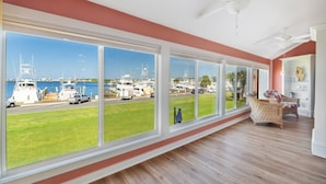 A spacious room with large windows overlooking a marina, a ceiling fan, and wicker furniture. - Amazing Marina Views | Baypoint Resort | Golf Course (Panama City Beach)
