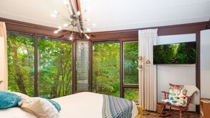 Un dormitorio con una cama grande, un sillón mecedora y un televisor.