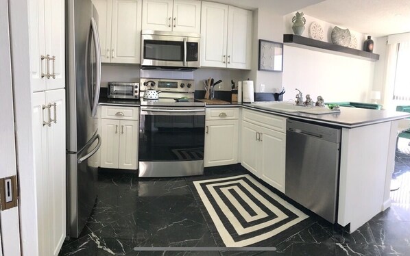 Kitchen features stainless steel appliances, a microwave, oven, and dishwasher, along with a sink and island.