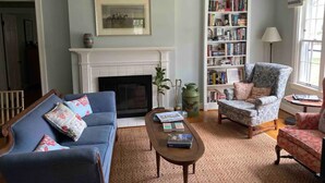 A living room with a fireplace, a bookshelf, a blue sofa, and a patterned armchair.