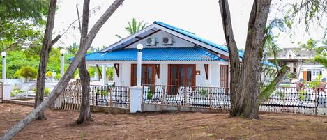 Una casa con techo azul, rodeada de árboles y una valla.