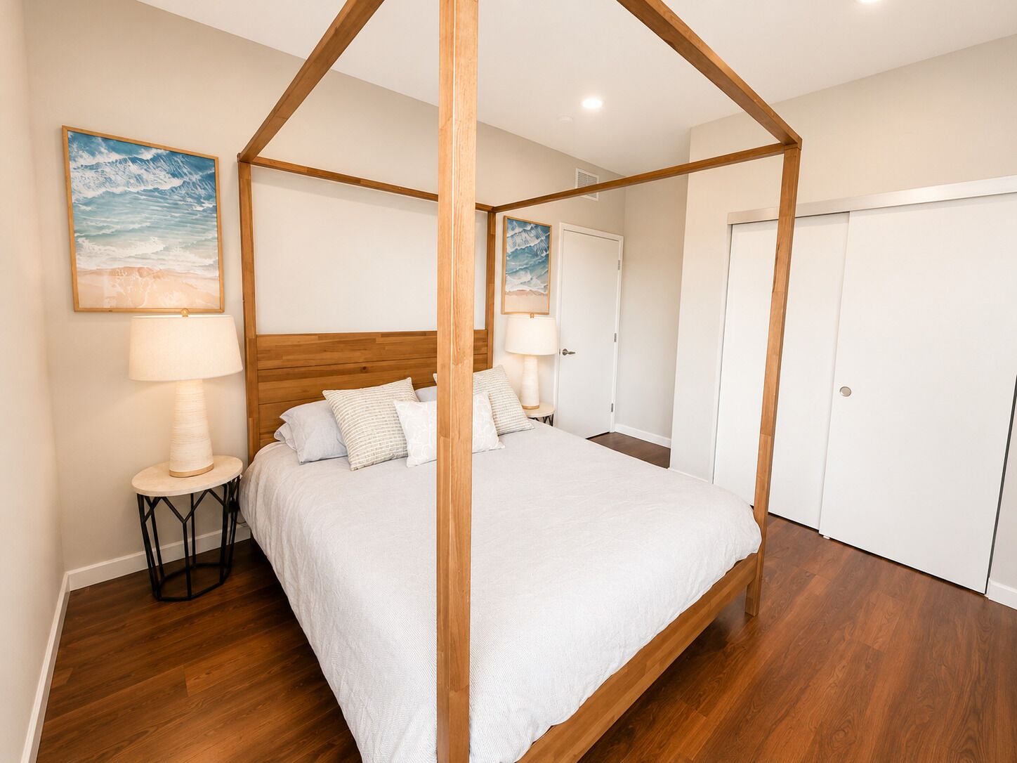 A four-poster bed with a wooden frame, two bedside lamps, and a white bedspread.