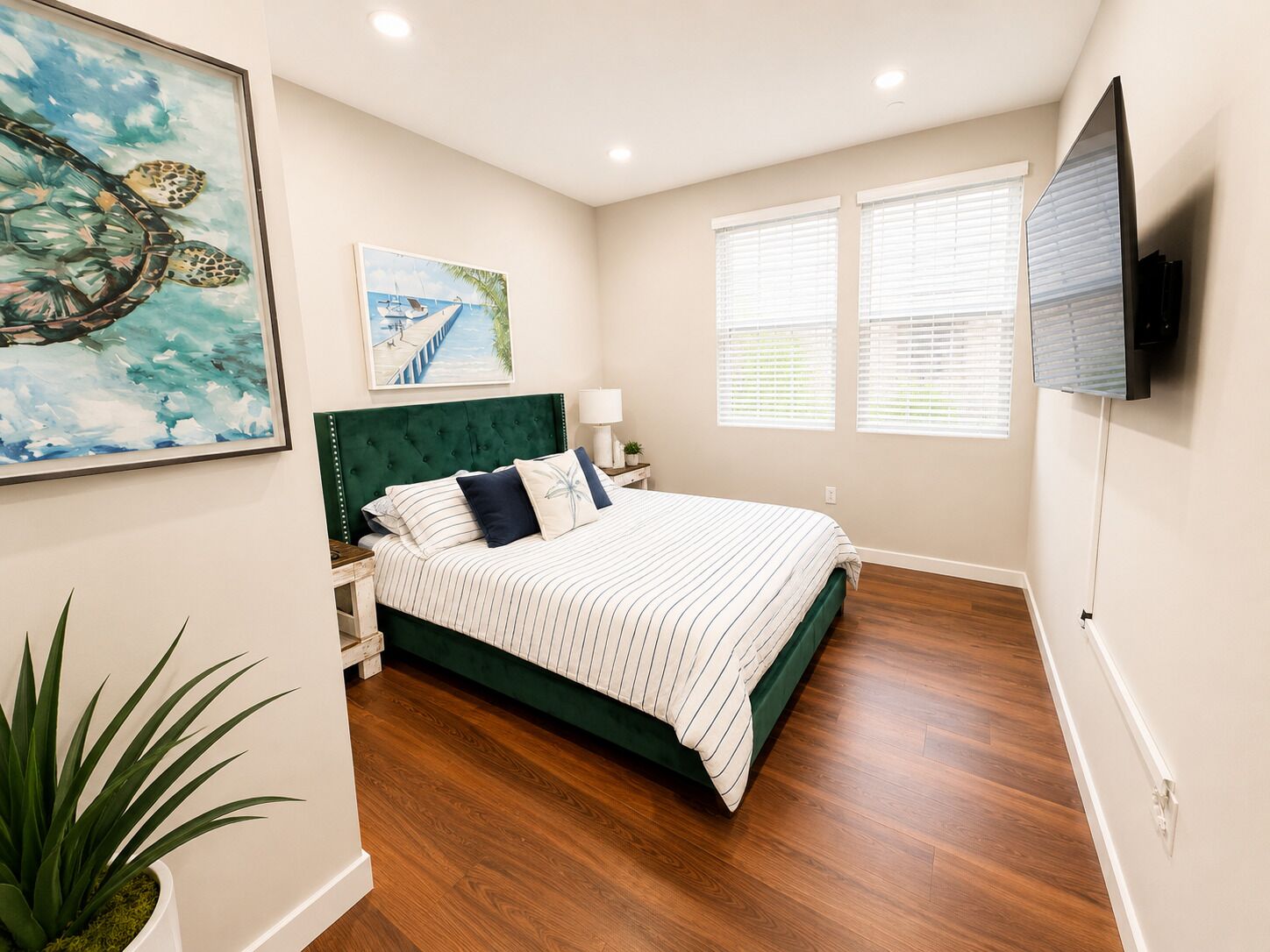 A bedroom with a bed, a nightstand, a lamp, a TV, and artwork on the walls.