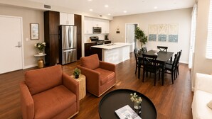 A modern kitchen with stainless steel appliances, a dining area with a black table and chairs, and a living room with two brown sofas. - Spacious 3 Bedroom, Close Venice Beach (Marina del Rey)