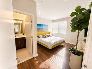 A bedroom with a bed, a nightstand, a potted plant, and a window with blinds. - Spacious 3 Bedroom, Close Venice Beach (Marina del Rey)