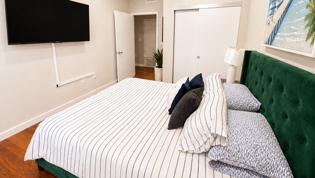 A bedroom with a bed, a television mounted on the wall, a door, and a painting. - Spacious 3 Bedroom, Close Venice Beach (Marina del Rey)