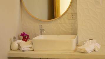 A bathroom with a white sink, a round mirror, and a towel rack.
