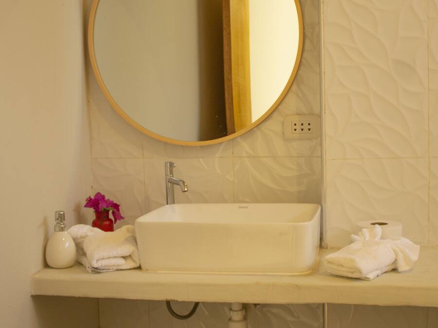 A bathroom with a white sink, a round mirror, and a towel rack.