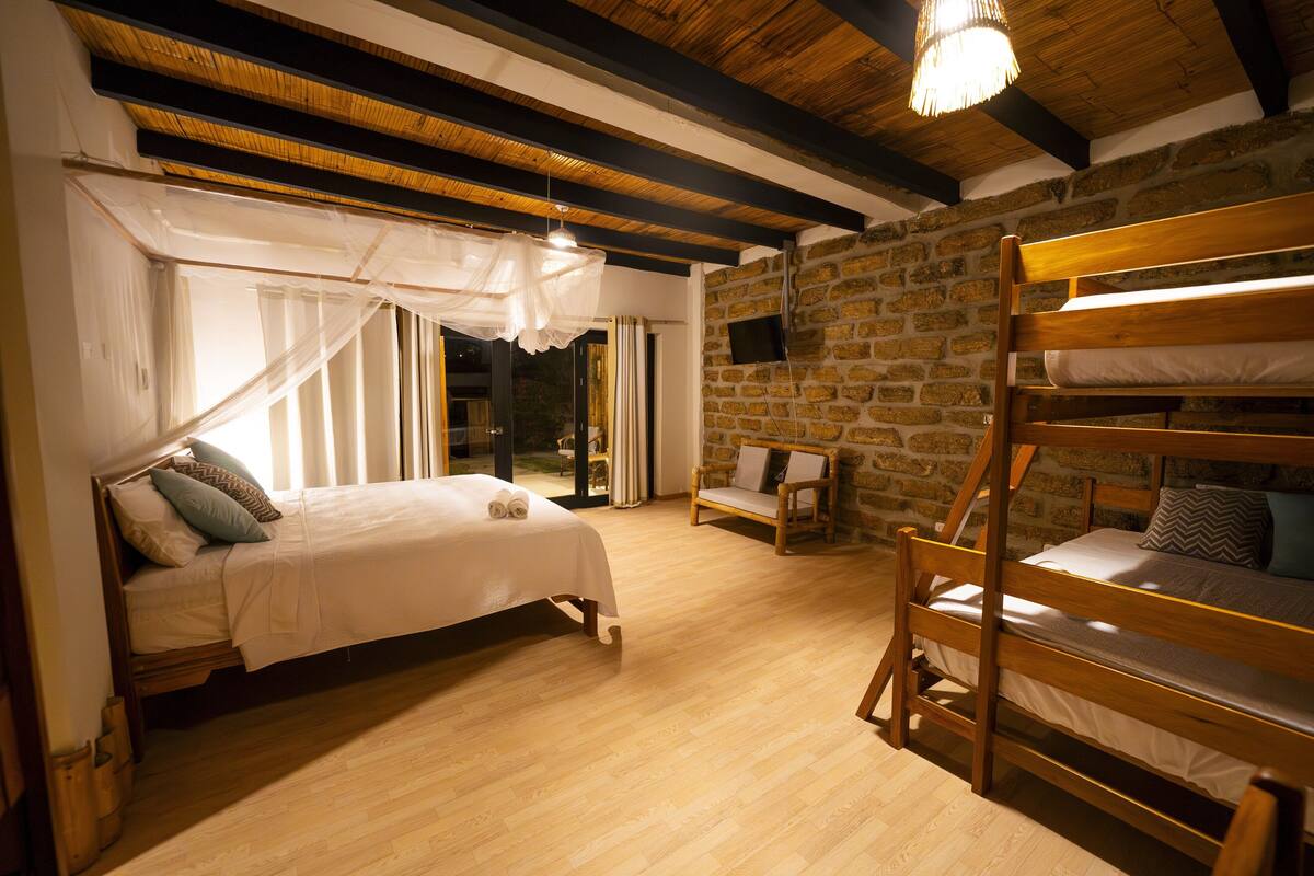 A room with a bed, a wooden bunk bed, and a stone wall.