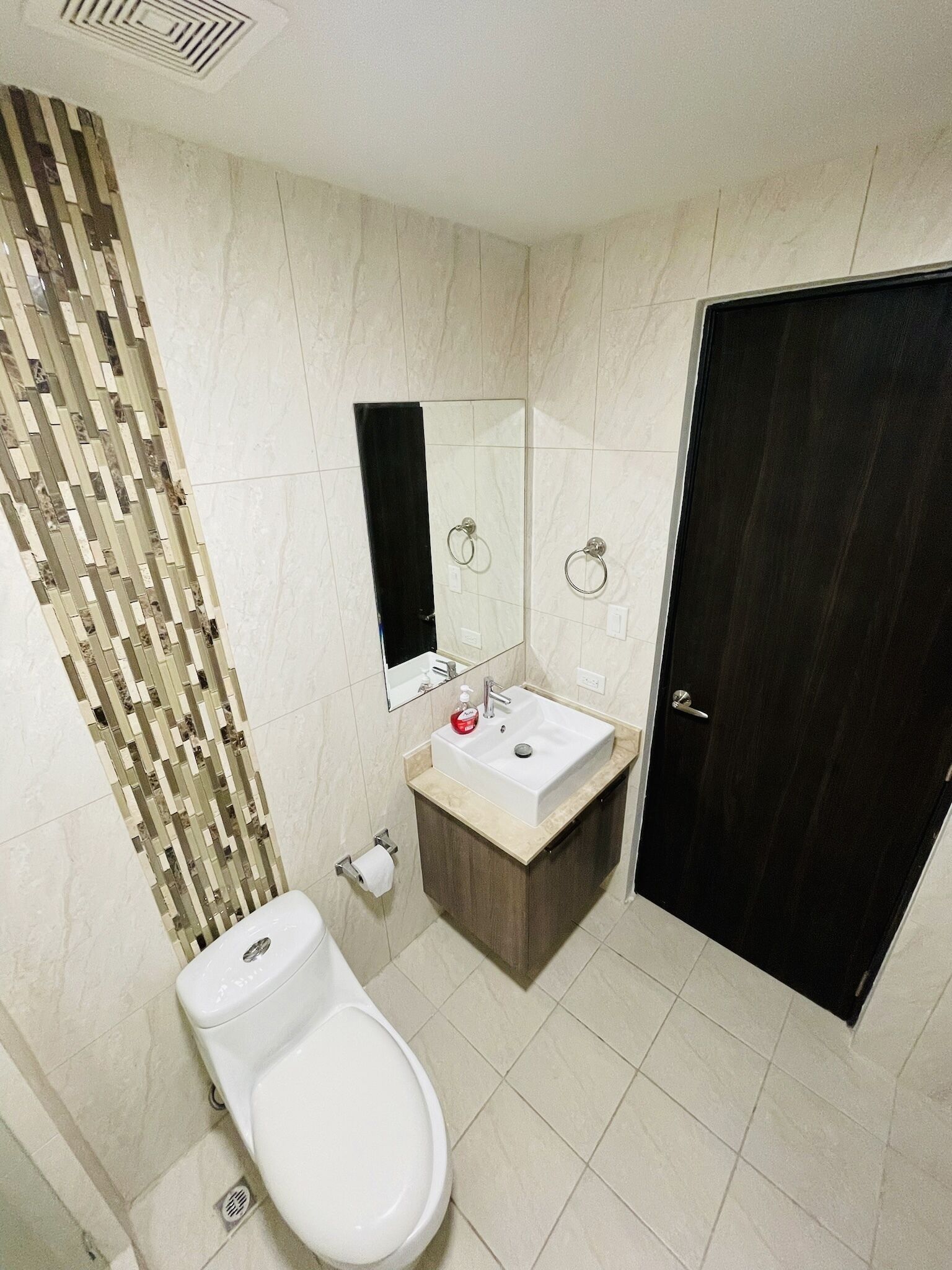 Et moderne badeværelse med toilet, vask og spejl.