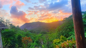 Un paisaje verde y exuberante con una montaña al fondo y una puesta de sol.
