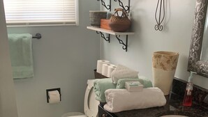 Een badkamer met toilet, wastafel en planken met toiletartikelen.
