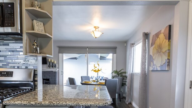 Cocina con encimera de granito, armarios blancos y una isla central con taburetes de bar.