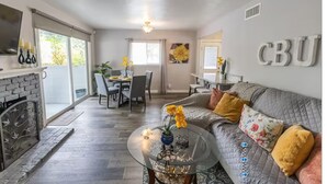 Una sala de estar amplia con chimenea, comedor y sofá con cojines decorativos.